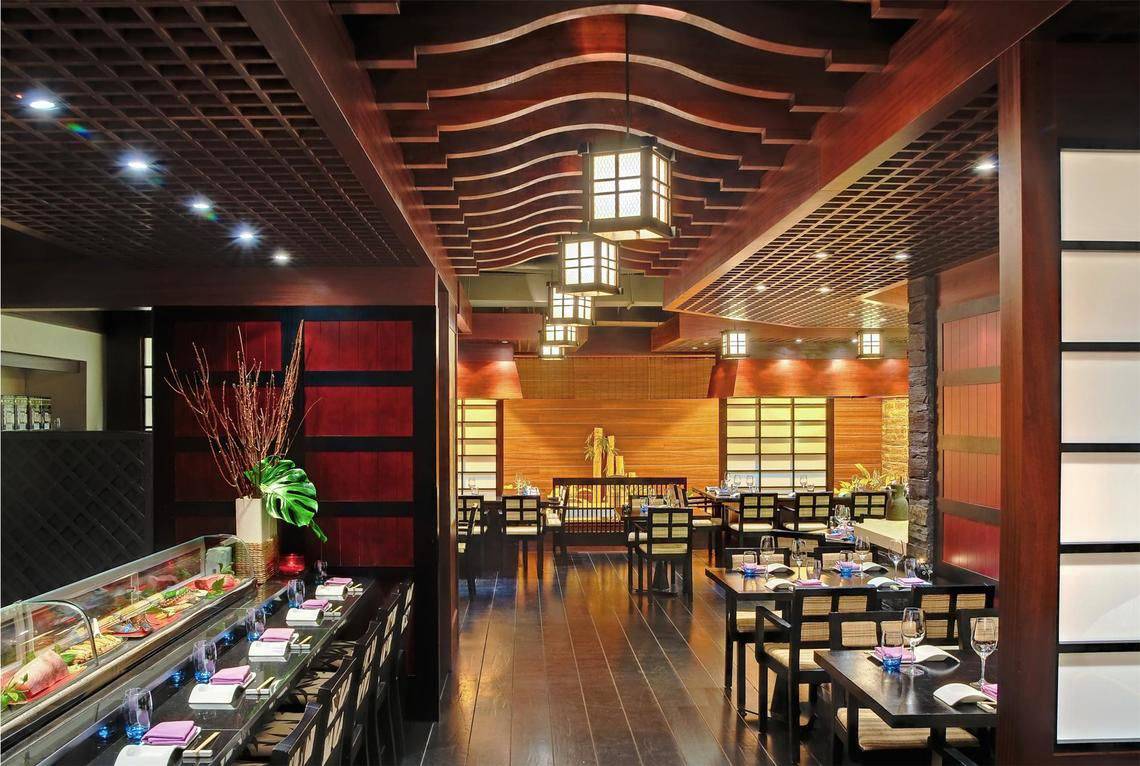 Innenansicht des Sushi-Restaurants im Tivoli La Caleta Tenerife Resort mit Holztischen, Stühlen und traditioneller Beleuchtung.