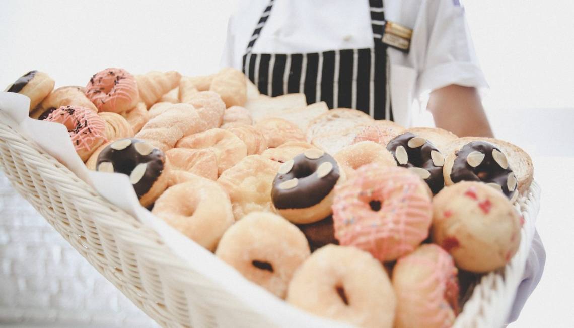 Ein Korb voller Gebäck, darunter Donuts und Croissants, wird von einem Mitarbeiter im Hotel Beyond Resort Krabi präsentiert.