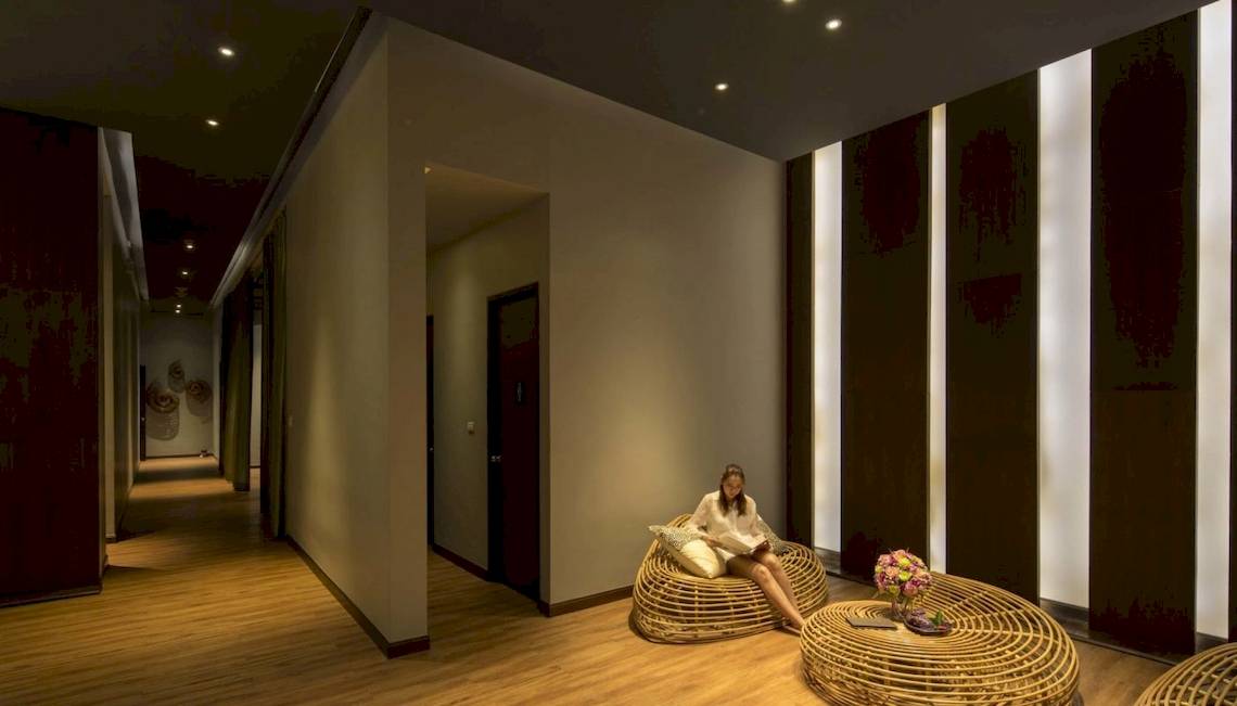 Eine Frau sitzt auf einem Korbstuhl im Hotellobby-Loungebereich des Beyond Resort Krabi.