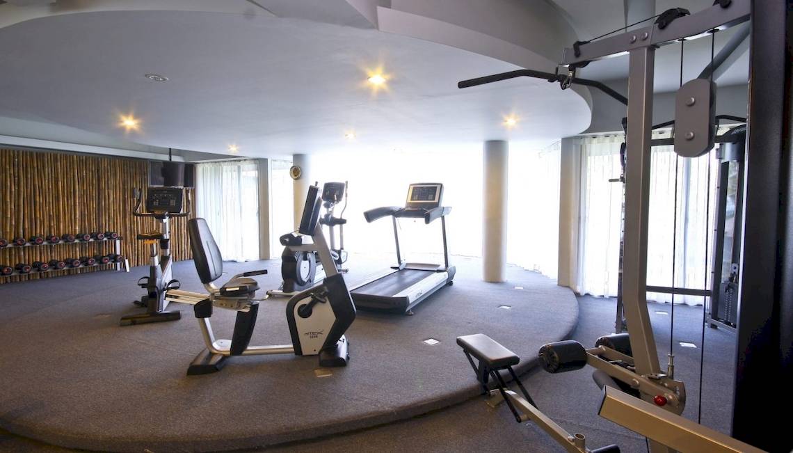 Fitnessstudio im Beyond Resort Krabi mit verschiedenen Geräten wie Laufband, Ergometer und Hantelbank.