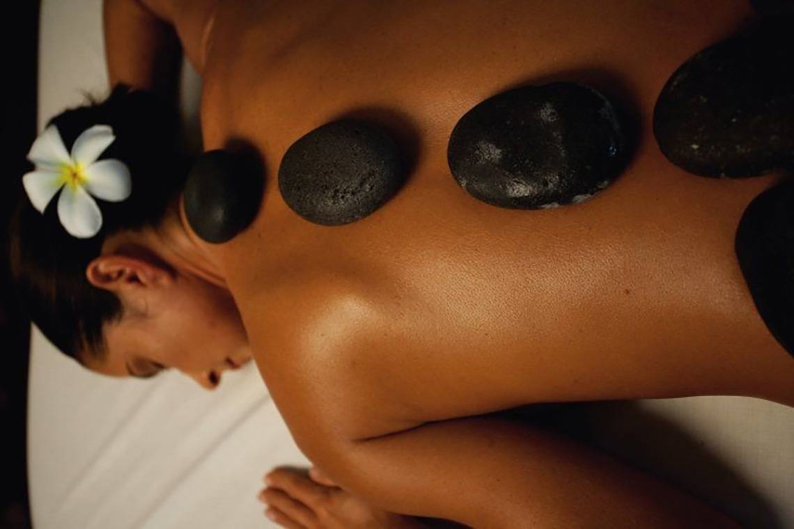 Frau genießt Rückenmassage mit Steinen im Ellaidhoo Maldives Spa