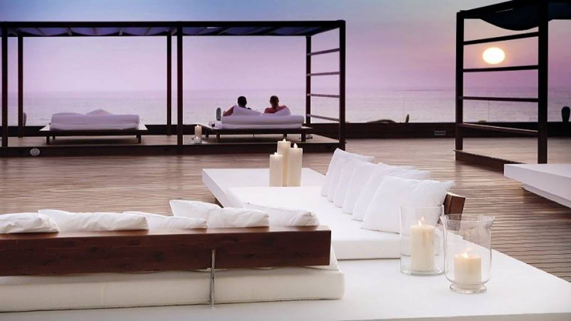 Loungebereich des H10 Gran Tinerfe Hotels mit Blick auf den Ozean und zwei Personen, die sich entspannen.