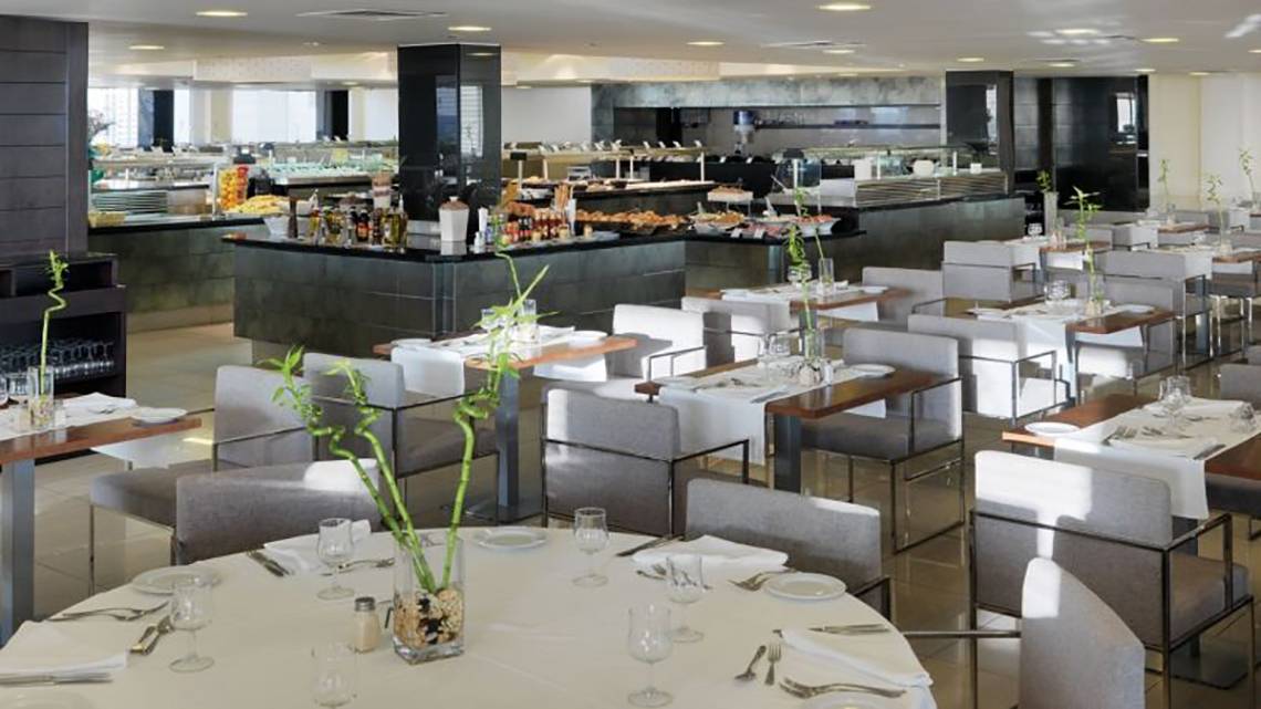 Das Restaurant des H10 Gran Tinerfe Hotels mit vielen gedeckten Tischen und einer Theke mit verschiedenen Speisen.