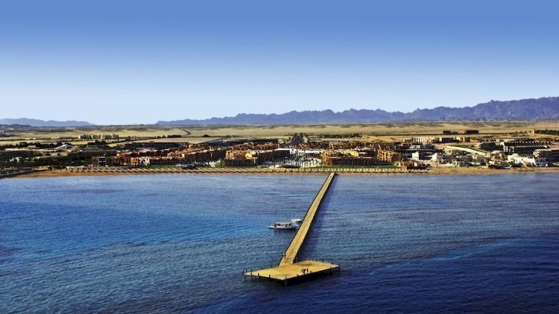 Luftaufnahme des Stella Gardens Resort & Spa Makadi Bay mit einer langen Brücke und einem Boot im Wasser.