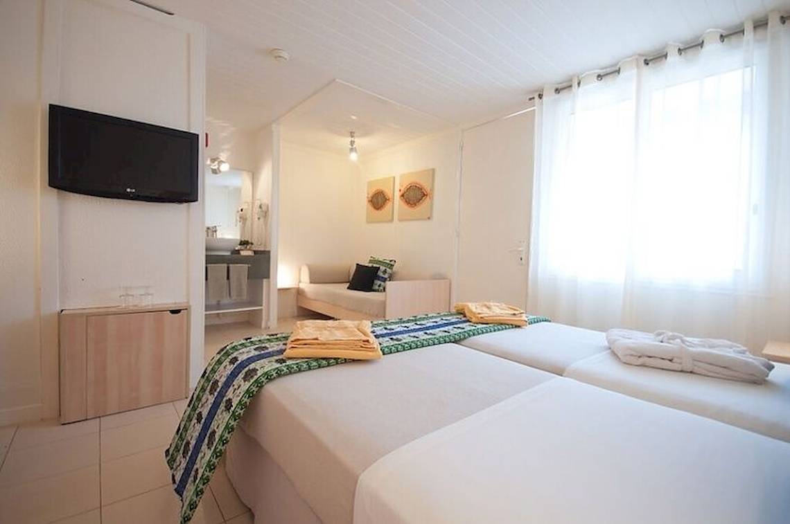 Doppelzimmer im Hotel Oasis Belorizonte mit zwei Betten, Fernseher, Badezimmer und Tageslicht.