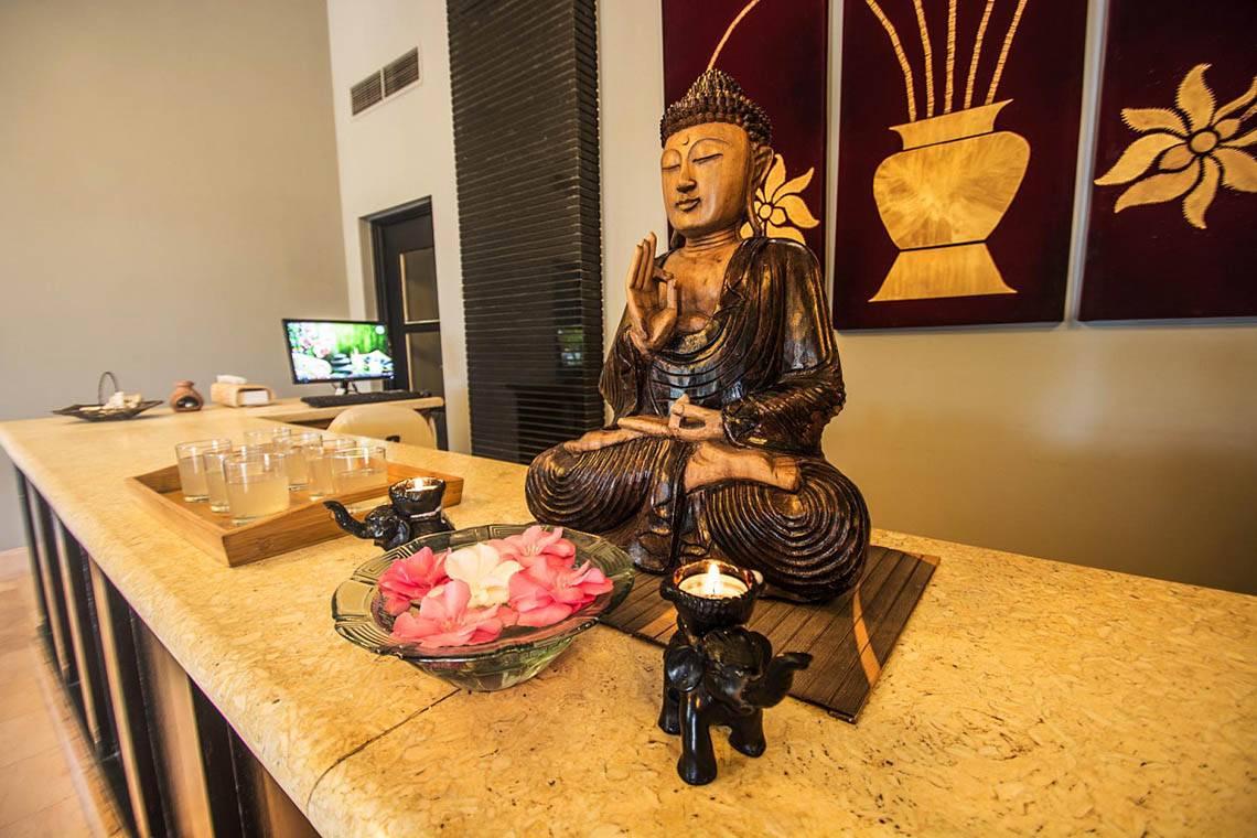 Buddha-Statue im Hotel-Lobby mit Blumen und Kerzen auf einem Tisch.