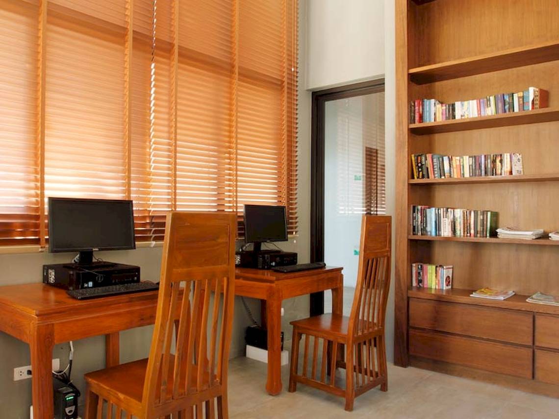 Arbeitsplatz mit zwei Computern, Stühlen und Bücherregal in einem Holzbüro.