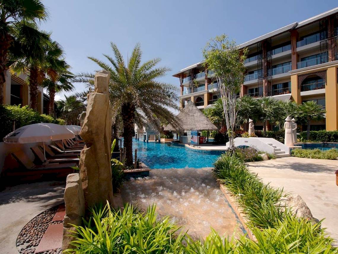 Außenbereich des Rawai Palm Beach Resorts mit Swimmingpool, Sonnenliegen und Palmen