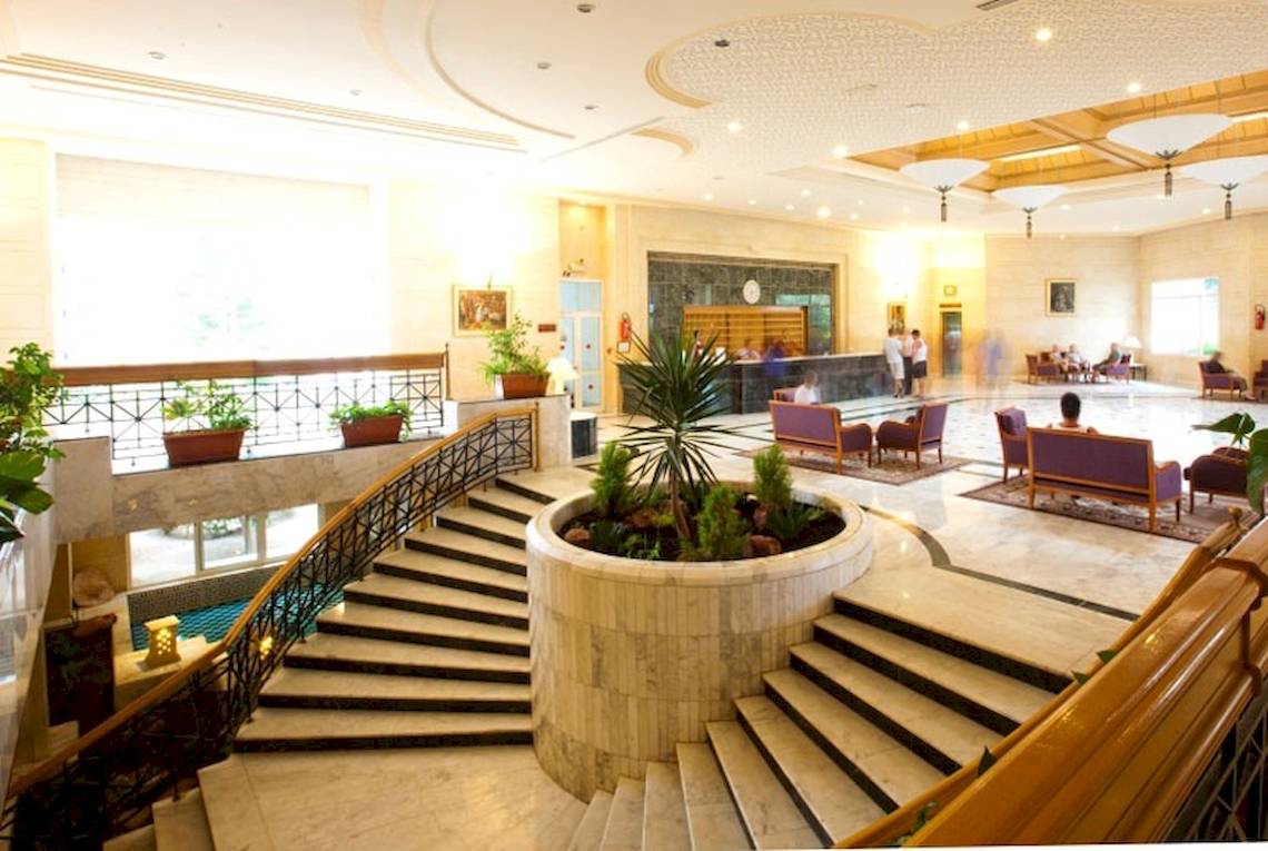 Lobby des El Mouradi Djerba Menzel Hotels mit zentraler Pflanze und Treppen.