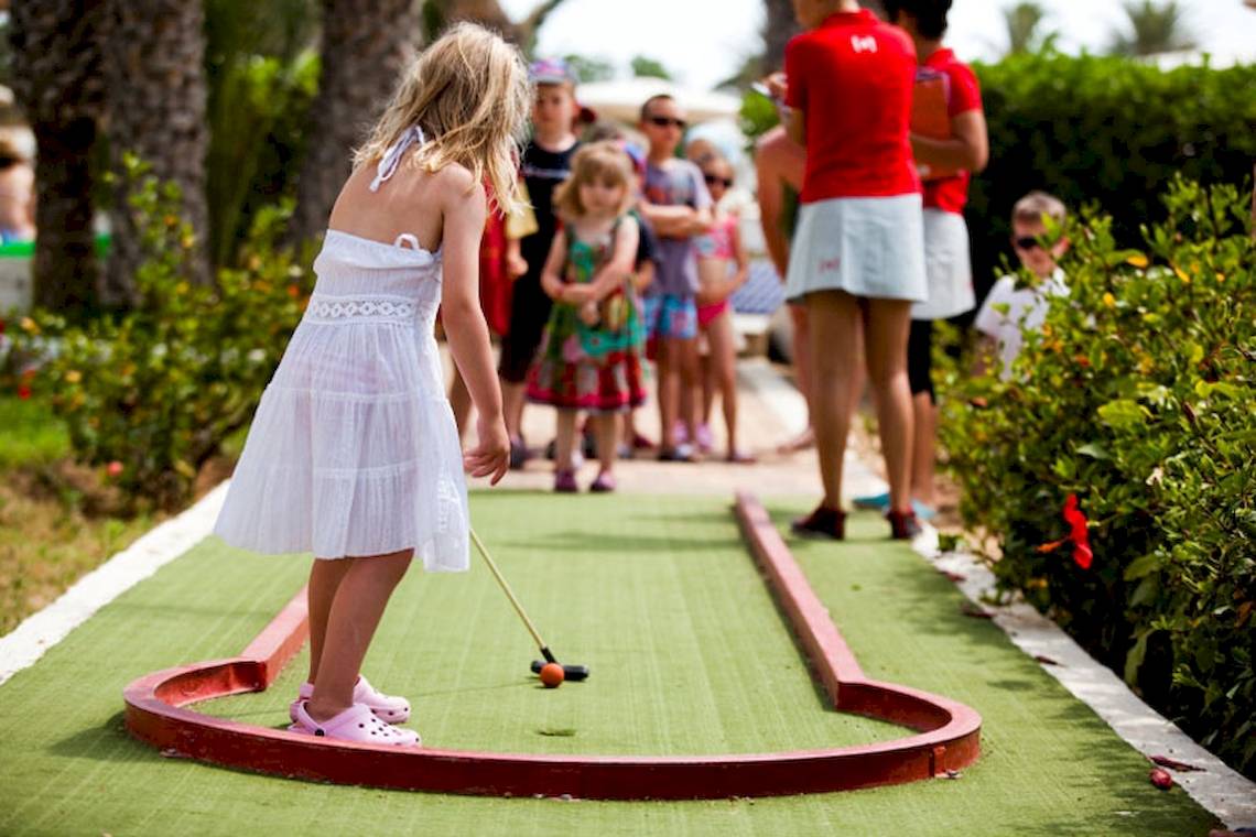 Ein kleines Maedchen spielt Minigolf im Freien im Hotel El Mouradi Djerba Menzel.