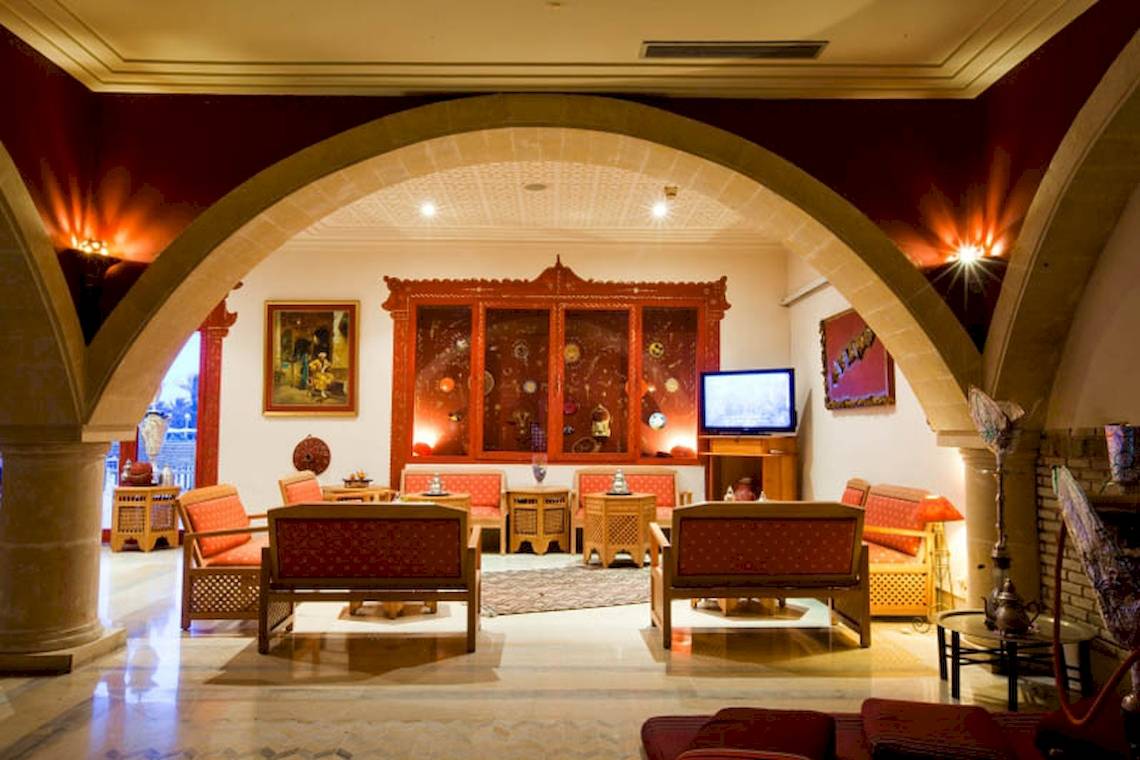 Loungebereich im El Mouradi Djerba Menzel Hotel mit rotem Dekor und Möbeln.