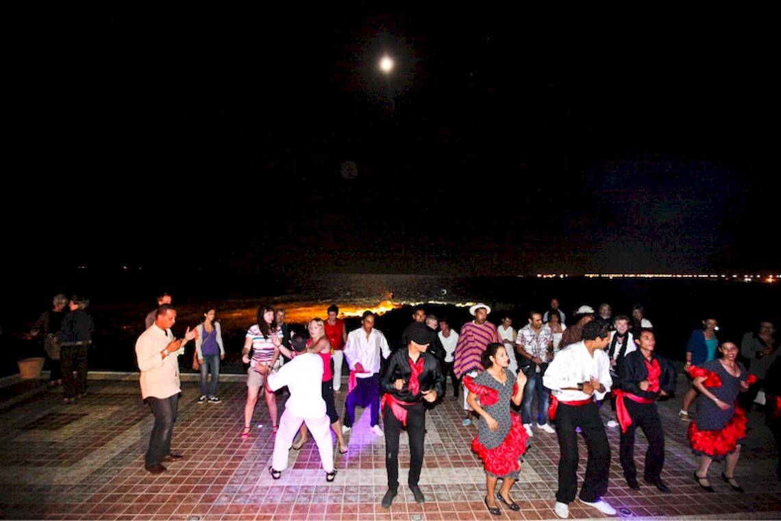 Nachtveranstaltung im Freien mit Menschen, die auf einer gepflasterten Fläche unter dem Mond tanzen, im Hotel El Mouradi Djerba Menzel.