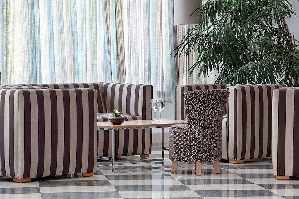 Lobby-Lounge des Lindos Bay Hotels mit gemusterten Sesseln und Tischen.