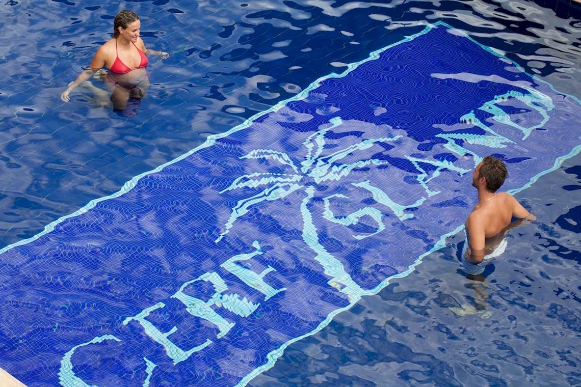 Zwei Leute schwimmen im Pool mit Cerf Island Resort Logo