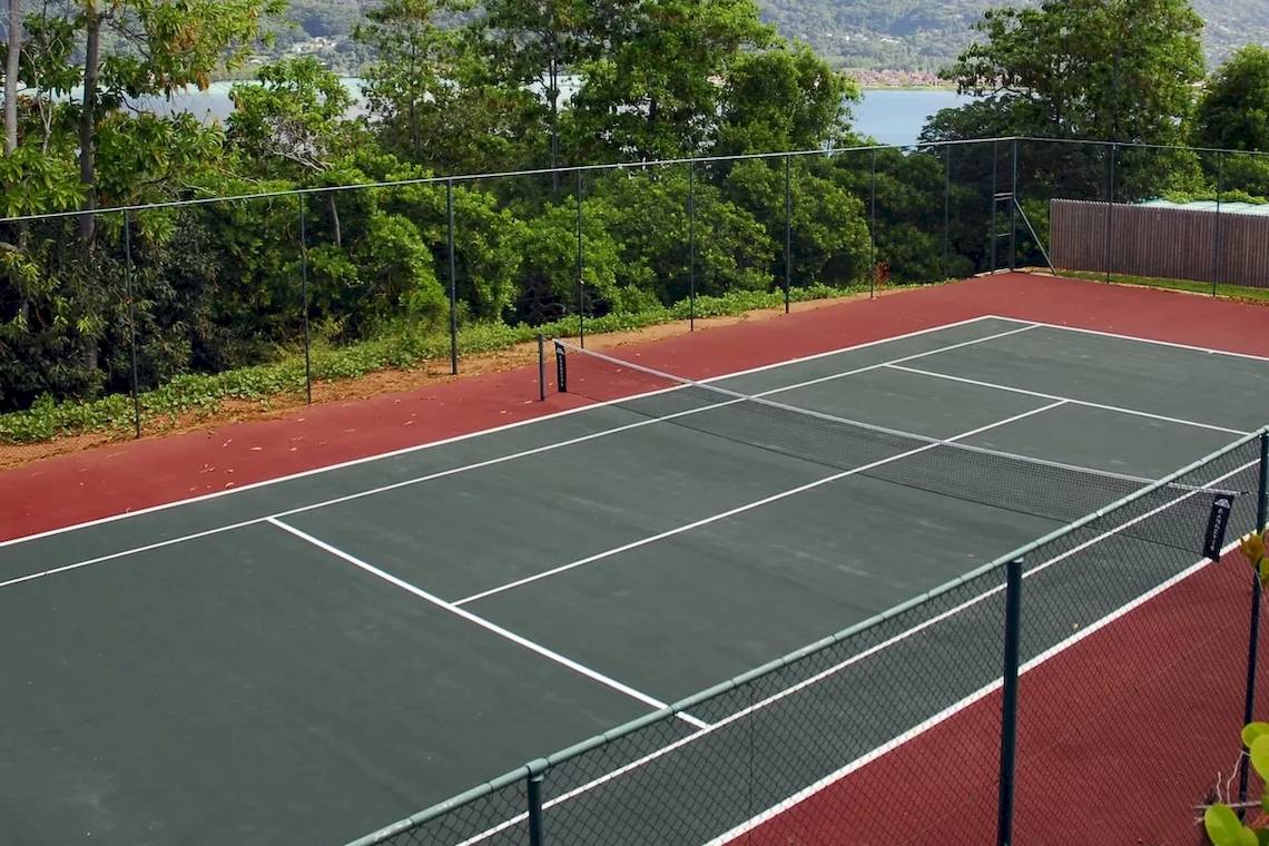 Tennisplatz des Cerf Island Resorts mit Blick auf den See und umgeben von Bäumen