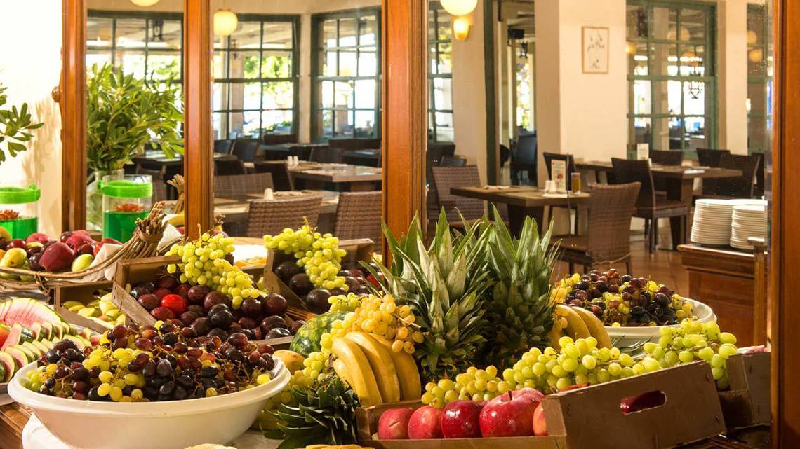 Frühstücksbuffet im Silva Beach Hotel mit verschiedenen Früchten wie Trauben, Äpfeln, Bananen und Melonen.