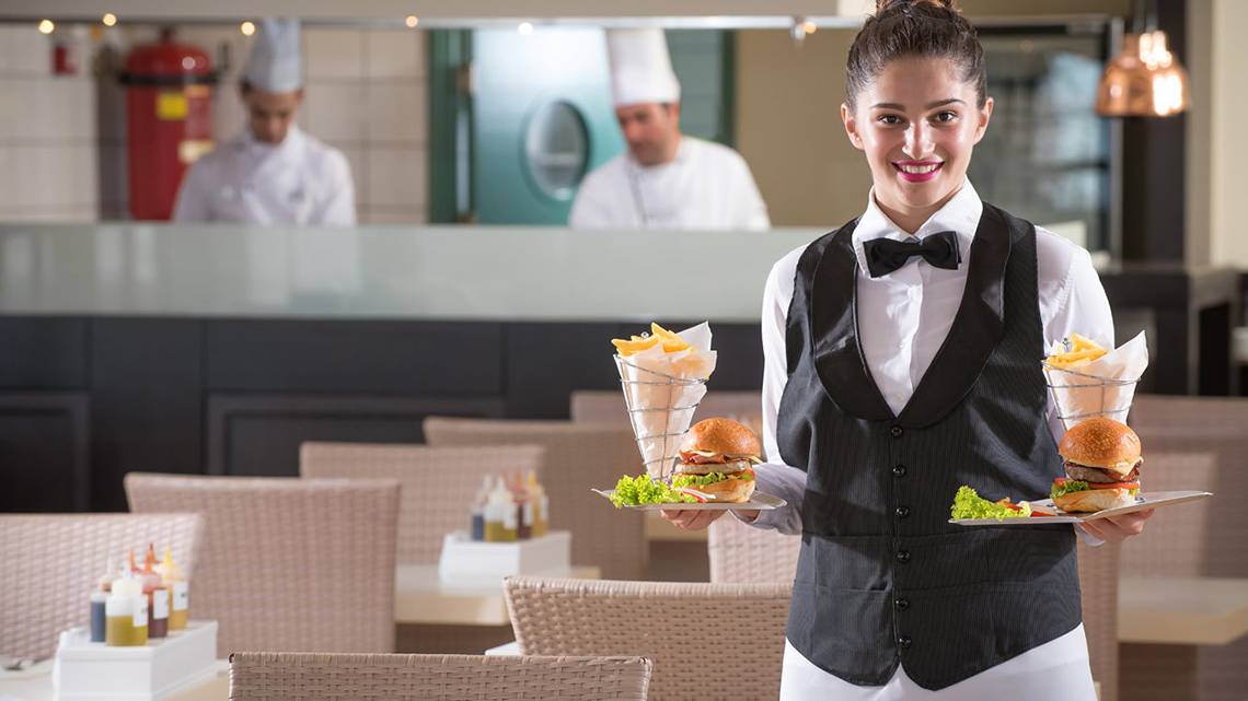 Eine Mitarbeiterin im Silva Beach Hotel serviert Essen in einer Speisekarte.