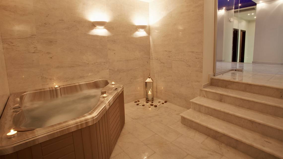 Jacuzzi-Bereich im Silva Beach Hotel mit Marmorwänden und Beleuchtung.