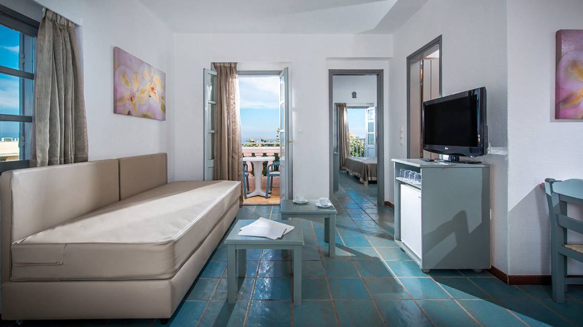 Innenansicht eines Zimmers im Silva Beach Hotel mit Sofa, Fernseher und Tisch.
