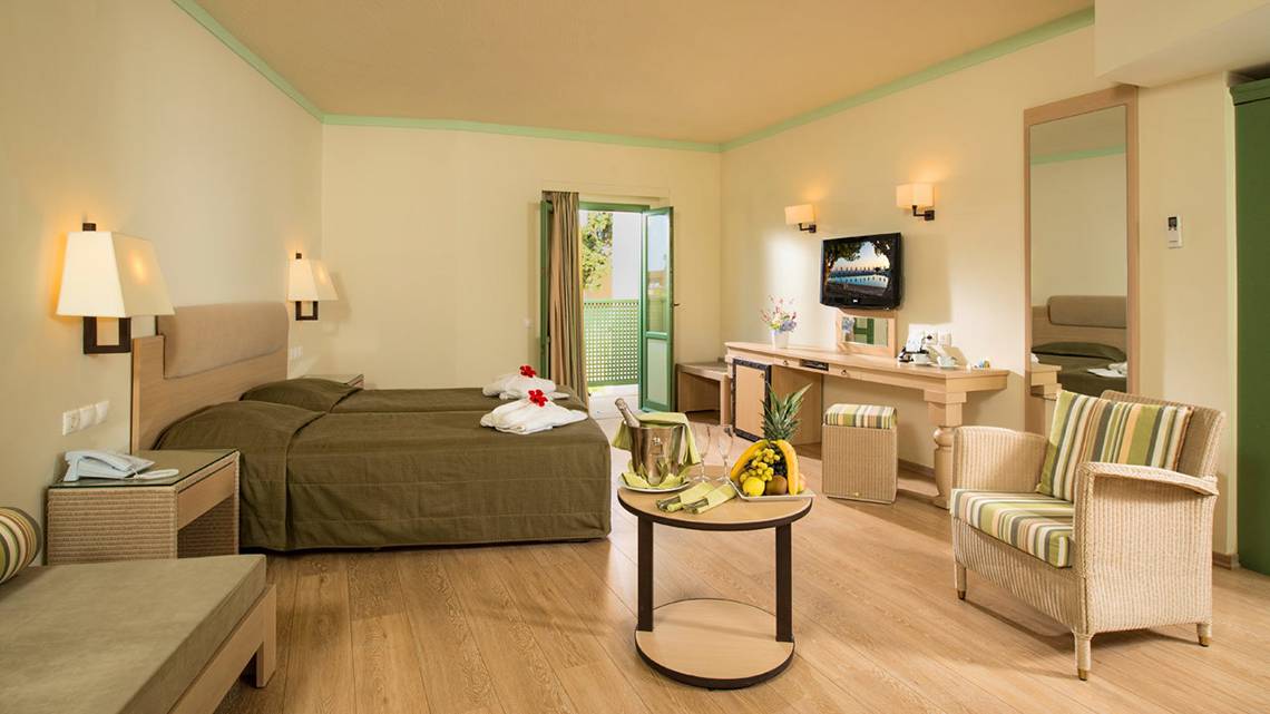 Innenansicht eines Doppelzimmers im Silva Beach Hotel mit zwei Betten, einem Tisch und einem Fernseher.
