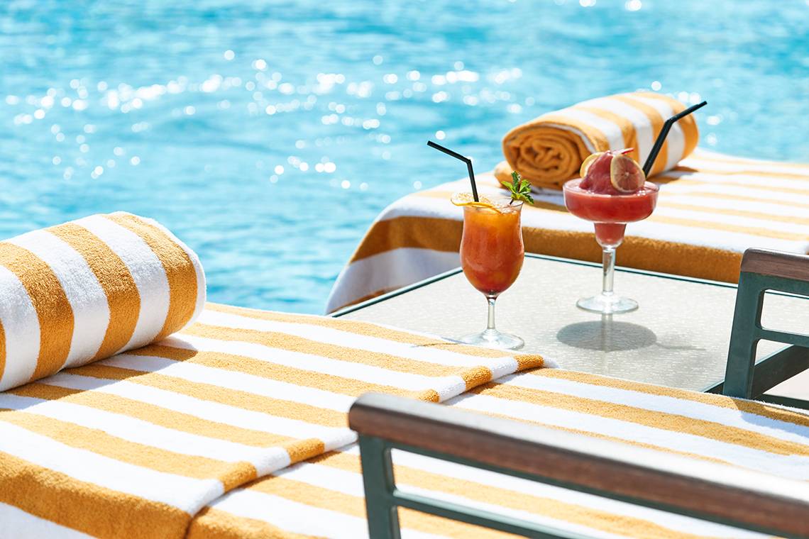 Getränke und Handtücher am Pool des Raffles The Palm Dubai