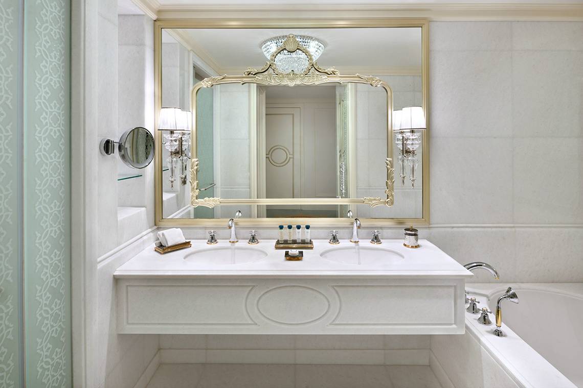 Badezimmer im Raffles The Palm Dubai mit einem großen Spiegel und zwei Waschbecken.
