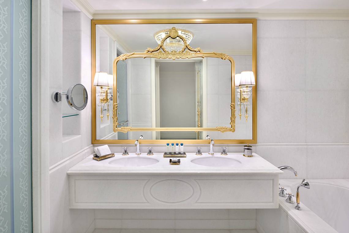 Badezimmer im Raffles The Palm Dubai mit Marmorspiegel und Goldakzenten.