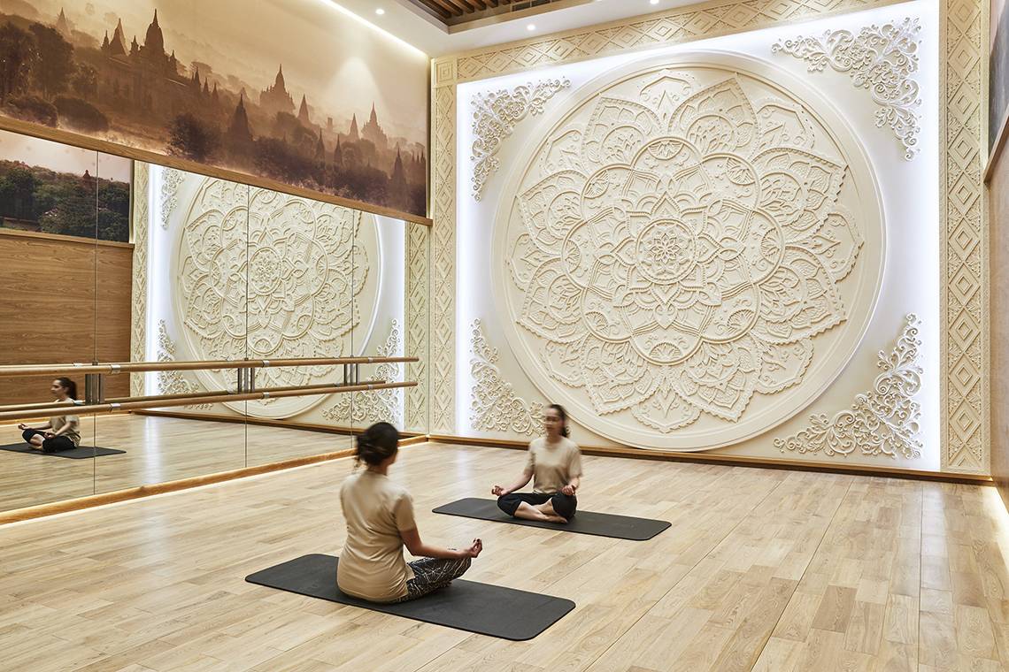 Drei Frauen praktizieren Yoga in einem eleganten Raum im Raffles The Palm Dubai.