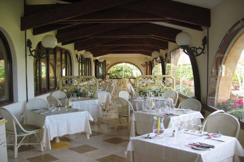 Restaurant des Baia Di Nora Hotels mit gedeckten Tischen und Blumenarrangements.