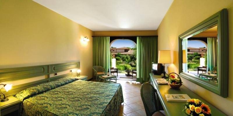 Hotelzimmer im Baia Di Nora mit Bett, Schreibtisch und Gartenblick