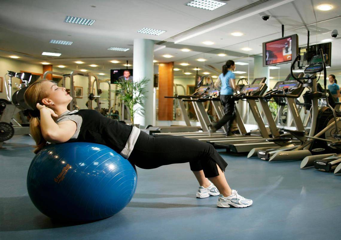 Frau im Fitnessstudio mit einem blauen Trainingsball im Swissotel Al Murooj Dubai