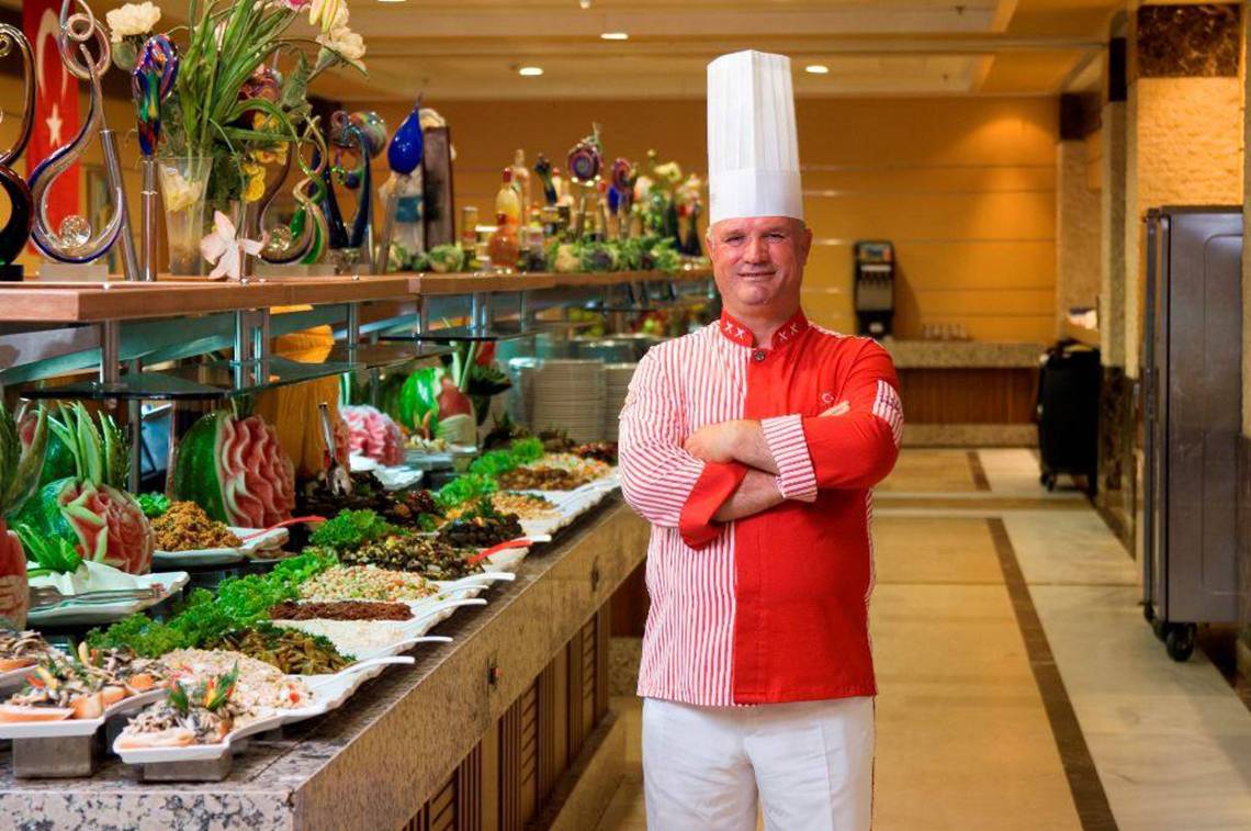 Ein Koch im Orange County Belek - Family Concept Hotel steht vor einem Buffet.