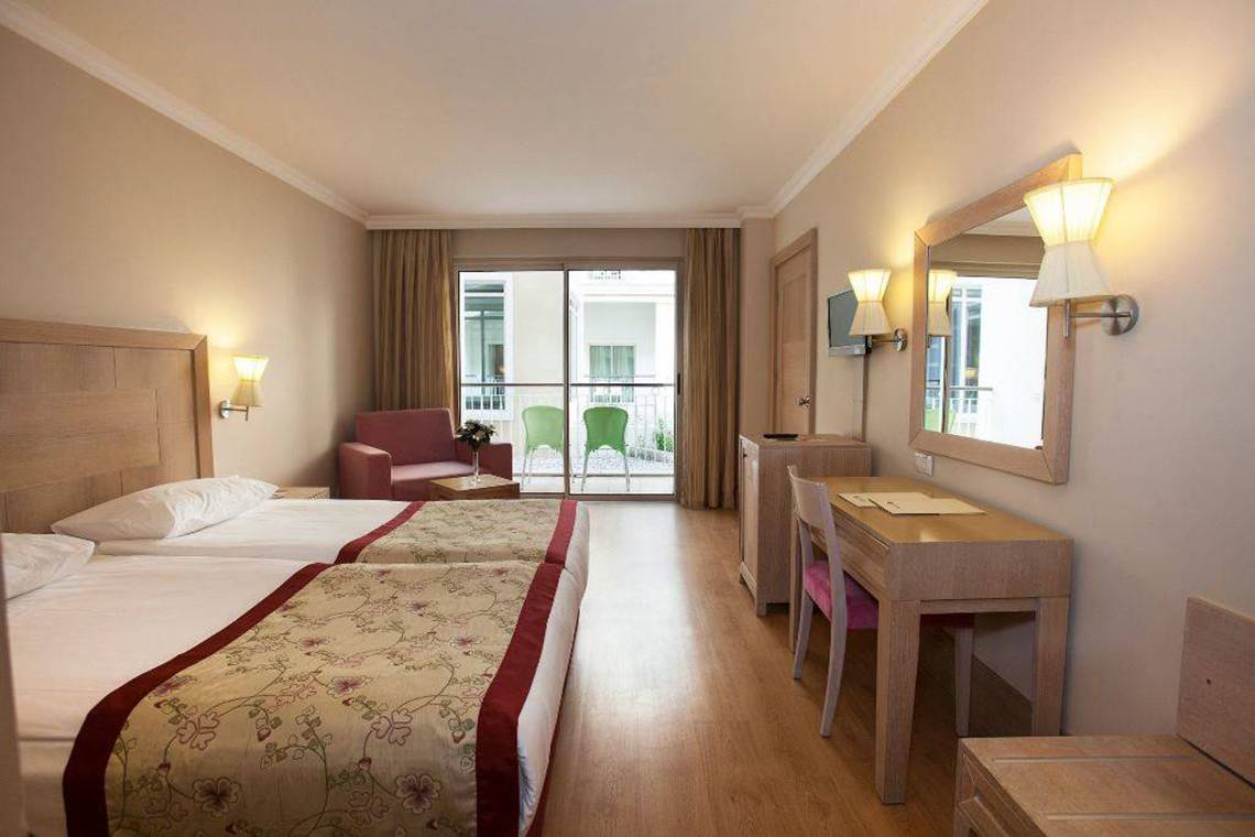 Doppelzimmer im Orange County Belek - Family Concept Hotel mit zwei Betten, Schreibtisch, Spiegel und Balkonzugang.