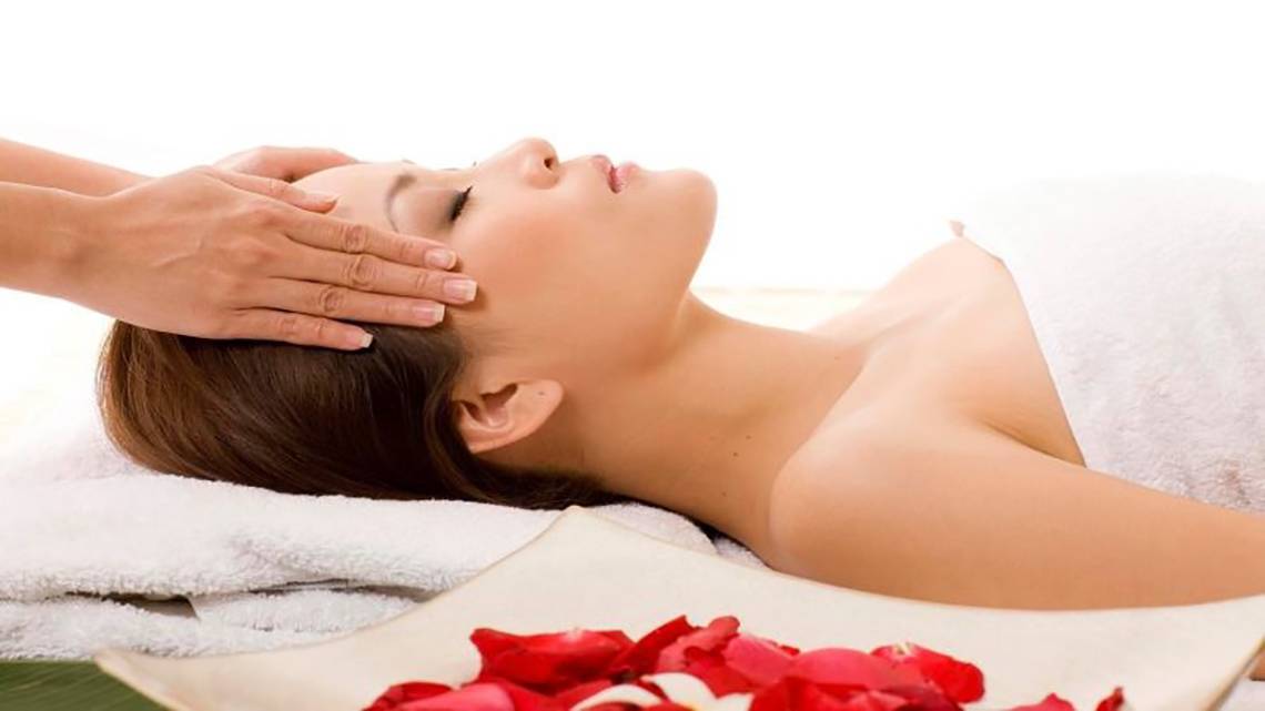 Frau genießt eine Kopfmassage im Hotel Barcelo Tenerife mit roten Rosenblättern.