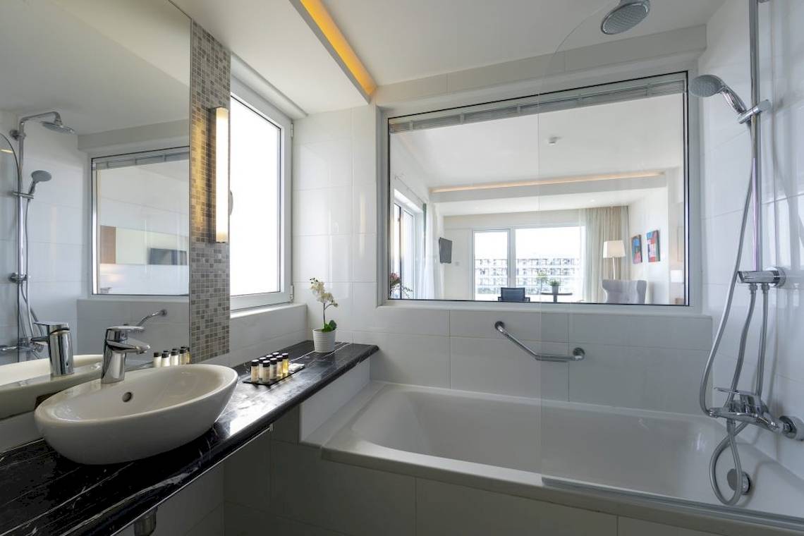 Badezimmer des Melissi Beach Hotel & Spa mit Badewanne und Dusche, Waschbecken und Spiegeln