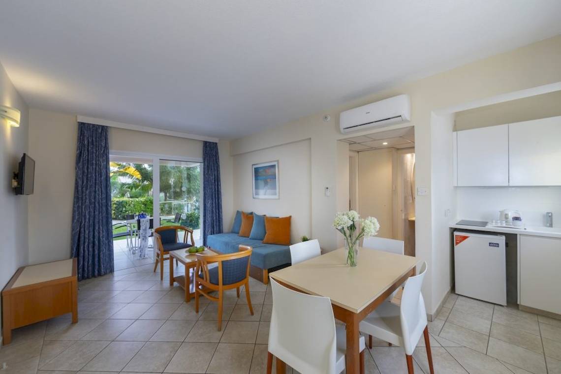 Innenansicht des Melissi Beach Hotel & Spa Wohnbereich mit Tisch, Sofa und Fenster.