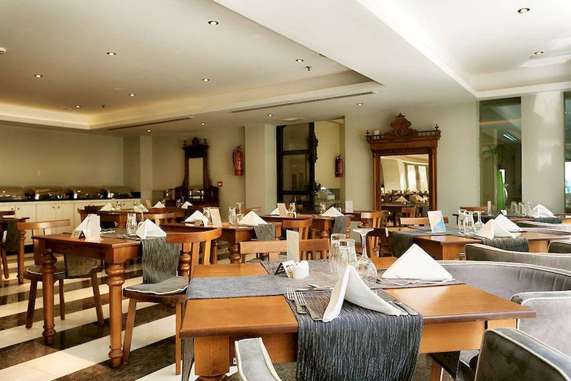 Innenansicht des Restaurants im Aegean Pearl Hotel mit gedeckten Tischen und Stühlen.