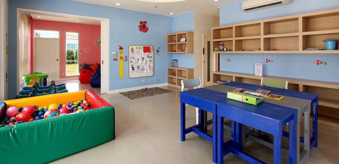 Kinderzimmer im Kantary Beach Hotel mit blauen Wänden, bunten Spielsachen und Regalen.