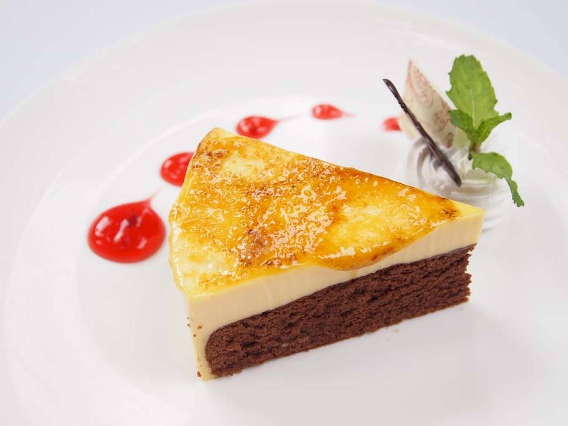 Schnitt eines Schokoladenkuchens mit Creme und Beeren auf einem weißen Teller