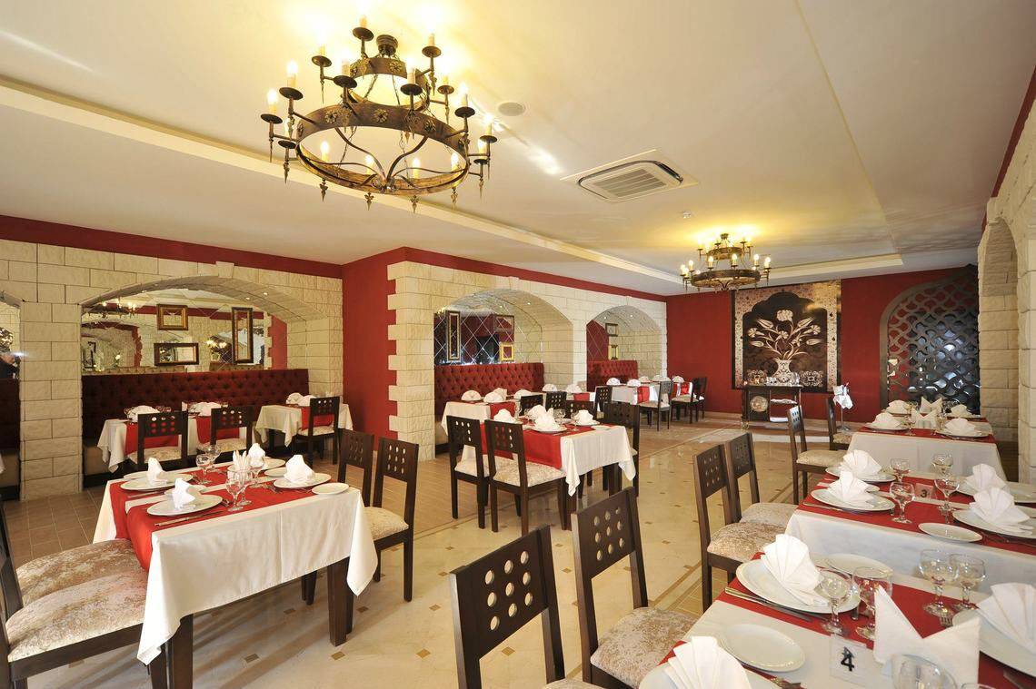 Innenansicht des Restaurants im Seaden Corolla Hotel mit gedeckten Tischen und Kronleuchtern.