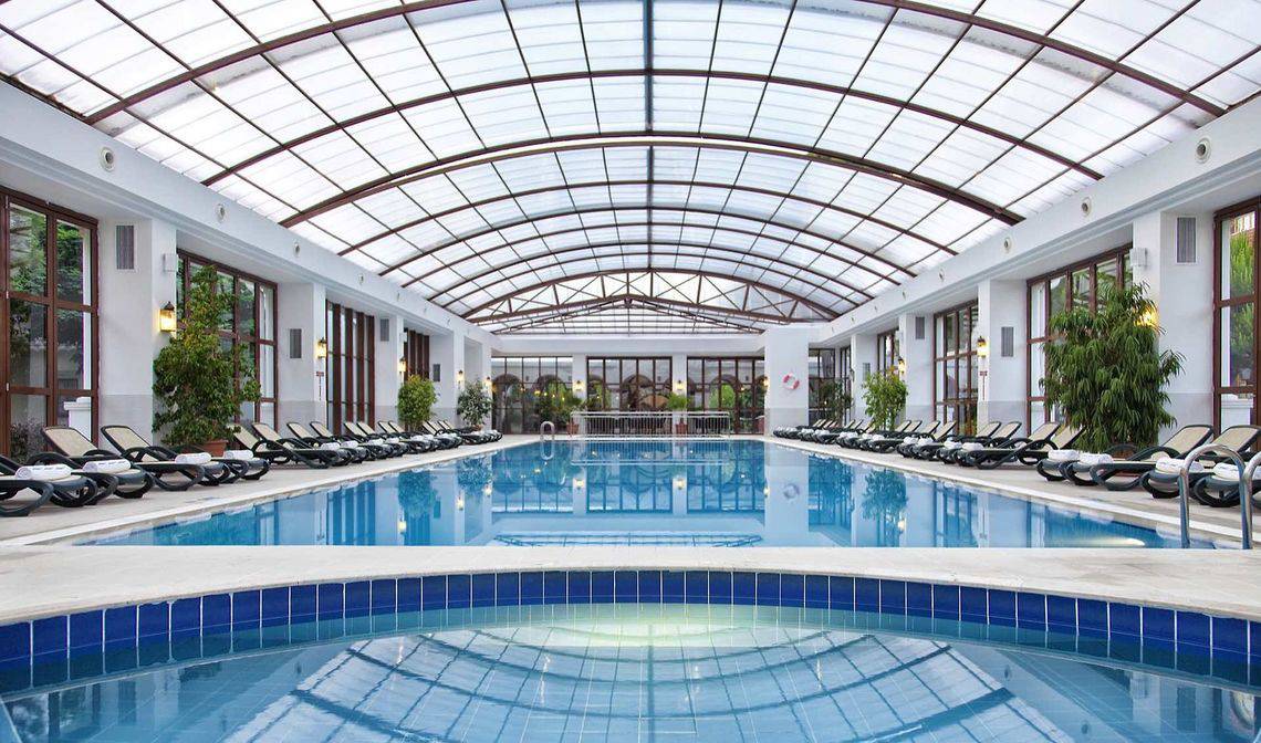 Innenpool des Kremlin Palace Hotels mit Lounge-Liegestühlen und Glasdach