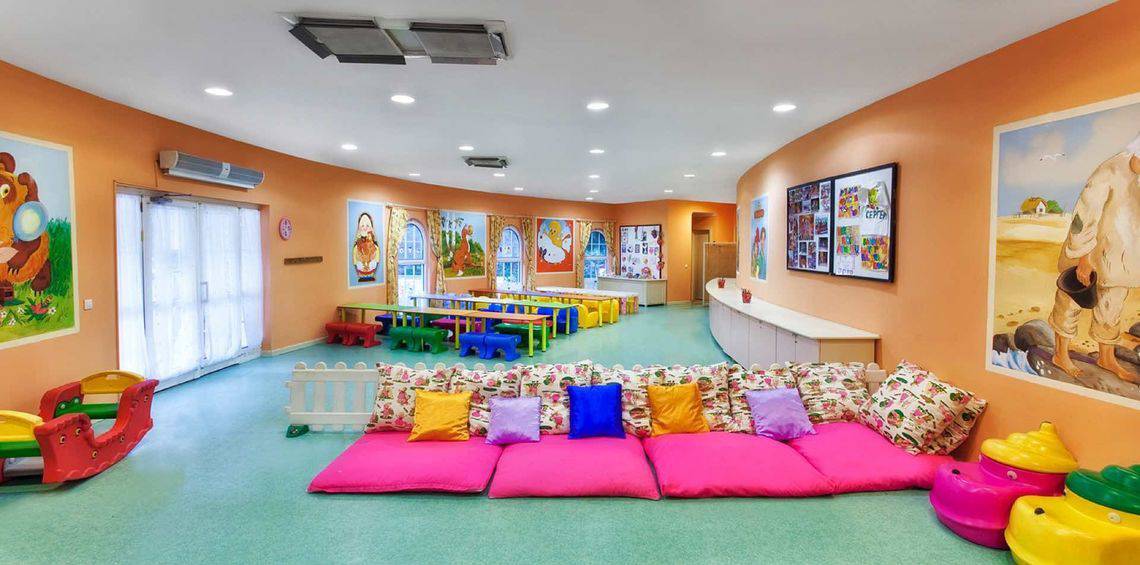 Kinderzimmer im Kremlin Palace Hotel mit bunten Möbeln, Kissen und Gemälden an der Wand.