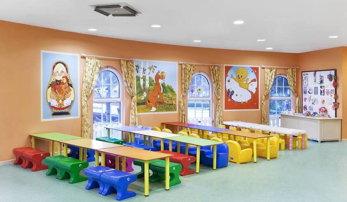 Ein Kinderzimmer im Kremlin Palace Hotel mit bunten Tischen und Stühlen, Wandgemälden und hellem Boden.