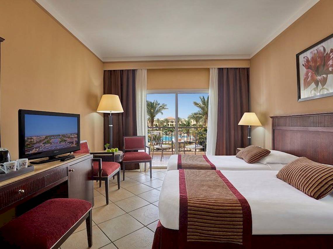 Doppelzimmer im Jaz Mirabel Beach Hotel mit zwei Betten und Fernseher.