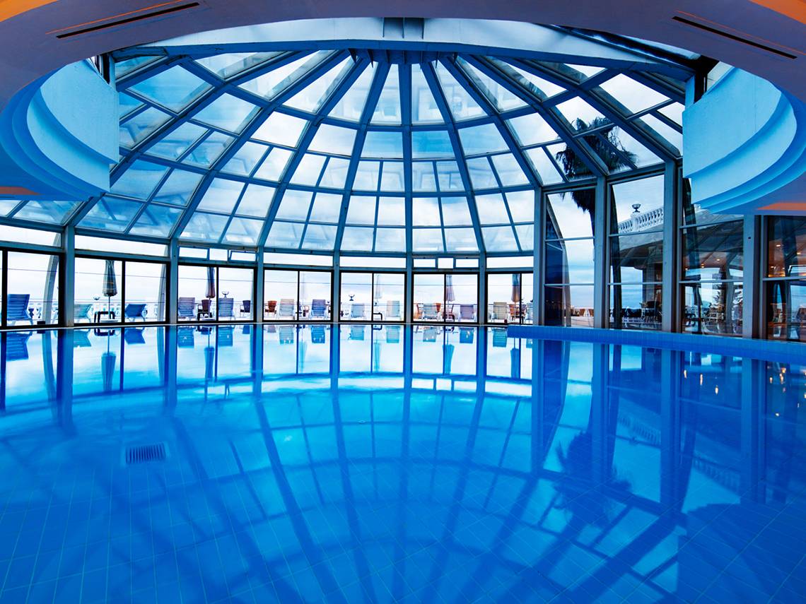 Innenpool des Sunrise Queen Luxury Hotel mit Glasdach und Blick auf den Ozean