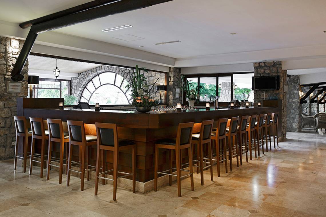 Barbereich im Marti Resort mit Holzstühlen und Steinwänden.