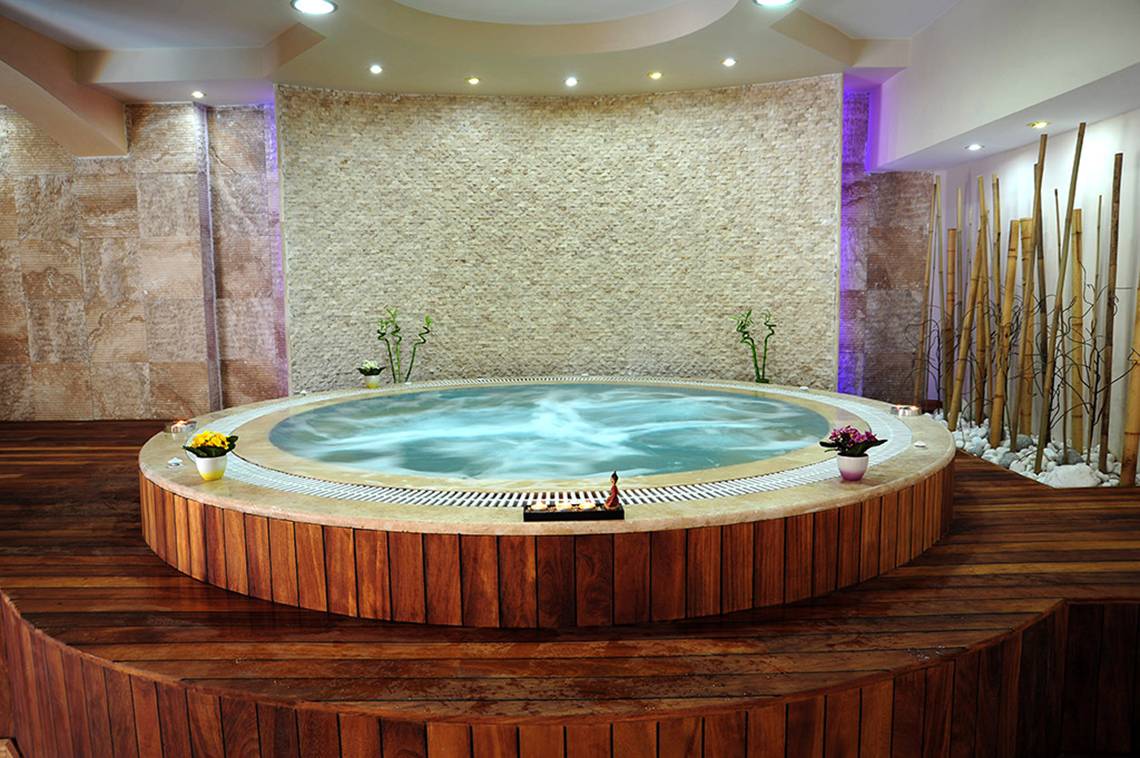 Jacuzzi im Marti Resort mit steinerner Wand und Holzboden.