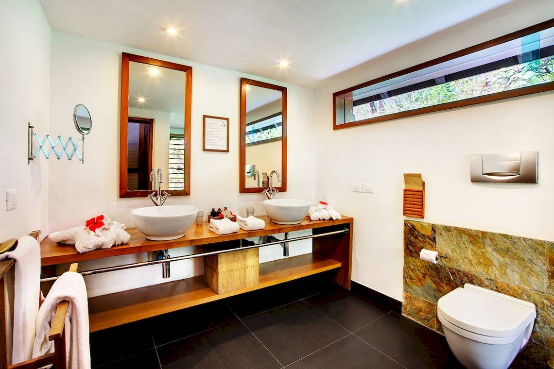 Badezimmer des Gangehi Island Resorts mit zwei Waschbecken, Spiegeln und einer Toilette.
