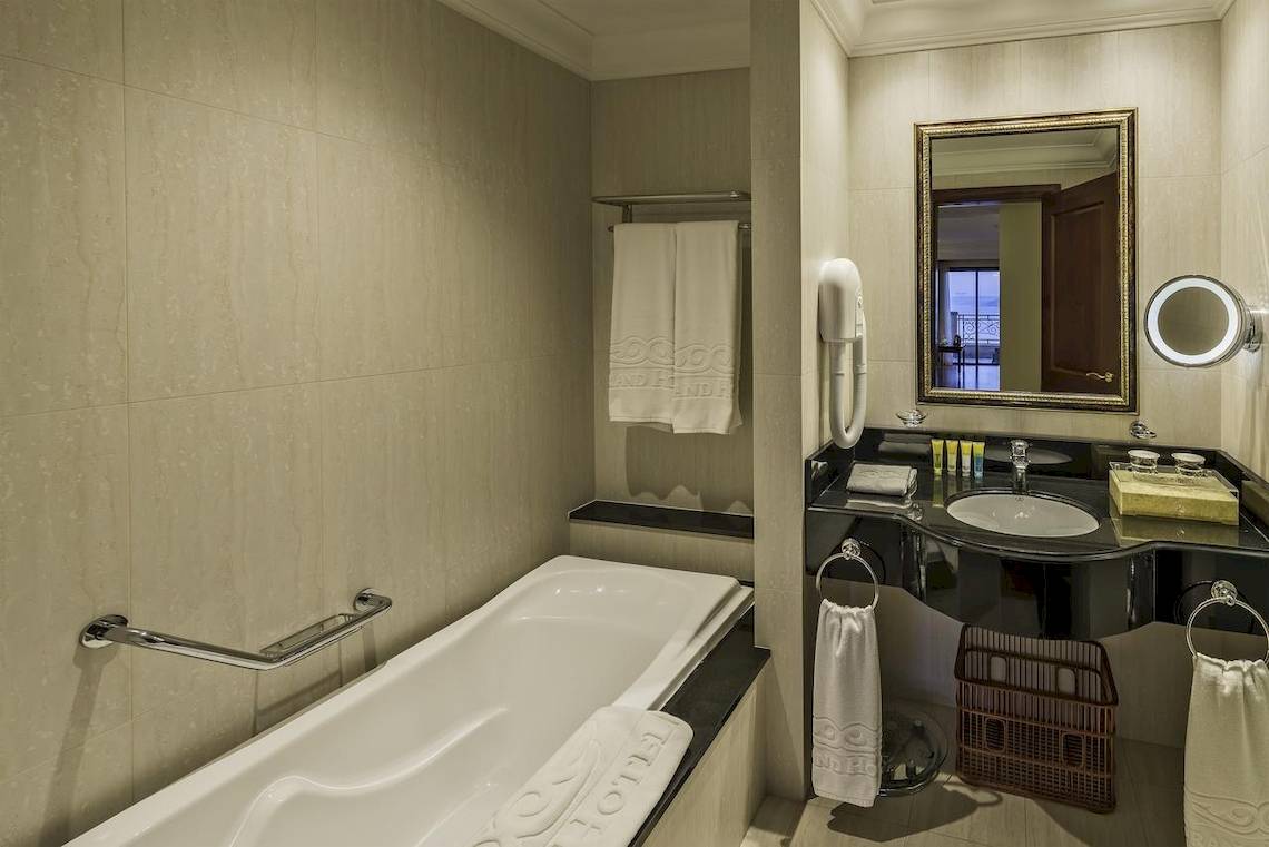 Badezimmer im Grand Hotel Gozo mit Badewanne, Waschbecken und Spiegeln.