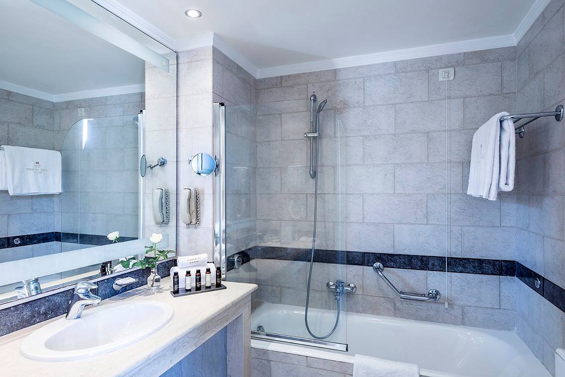 Badezimmer im Mitsis Lindos Memories Resort & Spa mit Badewanne, Dusche und Waschbecken.